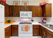 Thumbnail 8 of 36 - Spacious kitchen with honey brown toned cabinets with modern silver hardware, and white appliances.