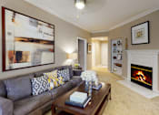 Thumbnail 6 of 36 - Spacious living room with wood-burning fireplace with glass doors, ceiling fan, crown molding, and built-in bookshelves at Tuscany Apartments in Houston.