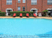 Thumbnail 23 of 26 - Luxury swimming pool with spacious sundeck, beautiful landscaping, and poolside lounge seating at Tuscany Villas in Houston.