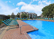 Thumbnail 5 of 30 - Huge swimming pool with spacious sundeck, poolside lounge chairs, beautiful landscaping, and scenic views at The Vanderbilt Apartments in Omaha, Nebraska