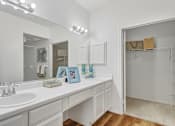 Thumbnail 6 of 40 - Spacious bathroom with double-sink, built-in vanity, extra-large mirror, lots of cabinet space, and tiled shower at Village on the Parkway Apartments in Houston Texas
