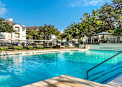 Thumbnail 22 of 40 - Luxury resort-style swimming pool with fountain, poolside lounges chairs, beautiful landscaping, lush landscaping and scenic views at Village on the Parkway Apartments