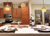 Thumbnail 26 of 36 - Luxury apartments next to the Galleria in Dallas with granite countertops, stainless steel appliances, built-in wine rack, kitchen island, and porcelain tile floor at Villa Piana Apartments in Dallas