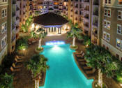 Thumbnail 12 of 36 - Luxury apartments with resort-style pool, palm trees, spacious sundeck with poolside lounge chairs, grilling station, fountains, and fitness center at Villa Piana Apartments in Dallas