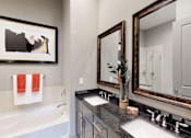 Thumbnail 14 of 45 - Luxury bath suite with double sink granite slab vanity top, frameless glass walk-in shower with separate soaking tub at Le Palais Apartments in Houston.