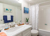 Thumbnail 9 of 22 - bright white bathroom with tiled shower and lots of cabinet space at Waters of Winrock Apartments in Houston TX