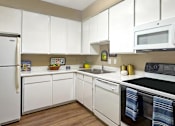 Thumbnail 2 of 38 - A kitchen with white cabinets and appliances.