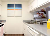 Thumbnail 12 of 42 - bright white kitchen with breakfast bar and wood plank floors at Woodlake on the Bayou Apartments
