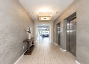 Thumbnail 4 of 12 - A hallway with a bench and a wallpapered wall.