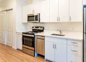 Thumbnail 7 of 12 - A kitchen with white cabinets and a black stove top oven.