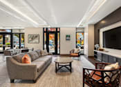 Thumbnail 6 of 6 - A living room with a grey couch and a brown chair.