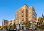 Thumbnail 8 of 16 - A multi-story building with a parking lot in front.
