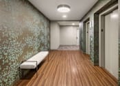 Thumbnail 5 of 8 - A long hallway with a bench and doors on the right.