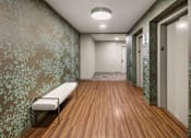 Thumbnail 12 of 16 - A long hallway with a bench and doors on the right.