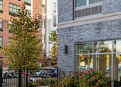 Thumbnail 11 of 16 - A bench is in the foreground of a brick building.