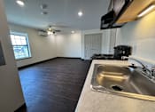 Thumbnail 6 of 14 - A kitchen with a sink and a stove top oven.