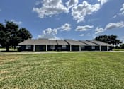 Thumbnail 10 of 14 - A large building with a grey roof is surrounded by a grassy field.