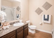 Thumbnail 1 of 11 - A bathroom with a toilet, sink, and a mirror.