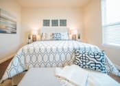 Thumbnail 8 of 11 - A bed with a white comforter and blue and white pillows.