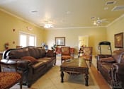 Thumbnail 7 of 8 - A living room with brown leather furniture and a ceiling fan.