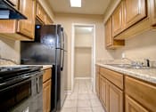 Thumbnail 3 of 8 - A kitchen with a black refrigerator and wooden cabinets.