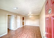 Thumbnail 1 of 8 - A room with a red door and a ceiling fan.