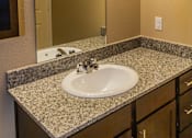 Thumbnail 13 of 14 - A bathroom with a granite countertop and a white sink.