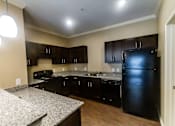 Thumbnail 7 of 14 - A kitchen with black appliances and brown cabinets.
