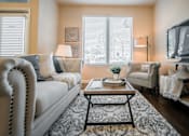 Thumbnail 7 of 11 - A living room with a white sofa, a coffee table, and a television.