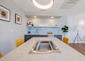 Thumbnail 10 of 32 - A modern kitchen with a marble table and yellow chairs.