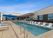 Thumbnail 1 of 27 - Resort-style swimming pool with lounge chairs and apartment building in the background