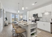 Thumbnail 4 of 27 - A modern kitchen with white cabinets and a large island
