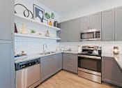 Thumbnail 19 of 32 - A modern kitchen with stainless steel appliances and wooden flooring.