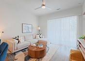 Thumbnail 32 of 32 - A living room with a white couch, a wooden coffee table, and a blue chair.