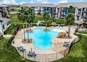 Thumbnail 15 of 17 - A large swimming pool surrounded by a black fence and palm trees.