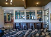 Thumbnail 25 of 27 - A room with a bar and a black and white checkered rug at The Grand at Manor Apartments, Manor, 78653