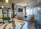 Thumbnail 19 of 27 - A modern living room with a stone fireplace and a grey sofa at The Grand at Manor Apartments, Manor, TX, 78653