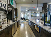 Thumbnail 10 of 27 - A modern kitchen with dark wood cabinets and a marble countertop at The Grand at Manor Apartments, Manor, Texas