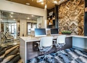 Thumbnail 22 of 27 - A modern office with a stone wall and two white chairs at The Grand at Manor Apartments, Manor