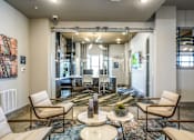 Thumbnail 18 of 27 - A living room with a large rug and a coffee table with a bowl of fruit on it at The Grand at Manor Apartments, Texas 78653
