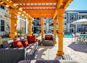 Thumbnail 20 of 27 - A patio with a yellow pergola and a pool table at The Grand at Manor Apartments, Manor, 78653