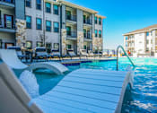 Thumbnail 4 of 45 - A swimming pool with a slide and a building in the background.