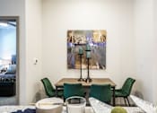 Thumbnail 23 of 27 - A painting hangs on the wall above a table with chairs around it at The Grand at Manor Apartments, Texas