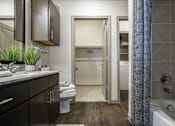 Thumbnail 16 of 27 - A bathroom with a toilet, sink, and bathtub at The Grand at Manor Apartments, Manor, TX