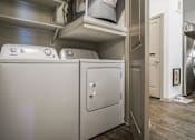 Thumbnail 21 of 27 - A white dishwasher is in a kitchen with a washing machine on top at The Grand at Manor Apartments, Manor, Texas