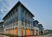 Thumbnail 27 of 27 - A modern building with a stone facade and arched windows at The Grand at Manor Apartments, Texas