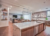 Thumbnail 17 of 26 - an open kitchen with a large center island and a dining room with tables and chairs  at Presidium Revelstoke, Fort Worth, TX