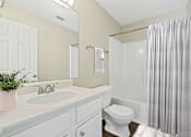 Thumbnail 23 of 24 - a white bathroom with a shower toilet and sink at Baldwin Farms Apartments, Robertsdale, AL