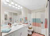 Thumbnail 22 of 23 - A bathroom with a white sink, toilet, and a mirror above the sink.
