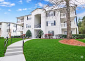 Thumbnail 3 of 19 - A white apartment building with a tree in front.